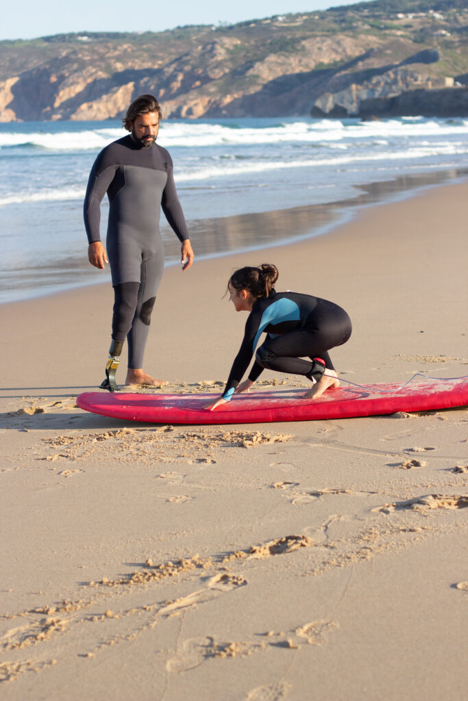 serious-coach-with-mechanical-leg-girl-near-ocean-mid-adult-man-teaching-little-dark-haired-girl-how-use-surfboard-learning-leisure-active-lifestyle-concept-683x1024.jpg